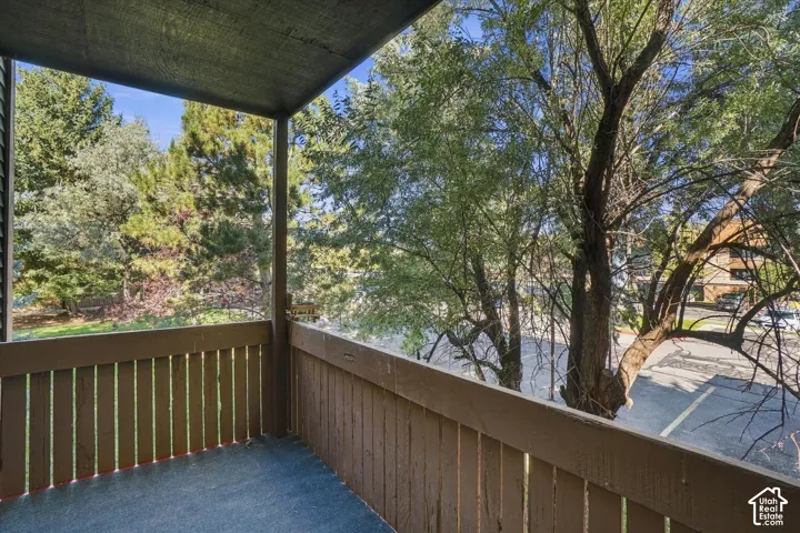 Covered balcony featuring wood railing and a surrounding natural landscape