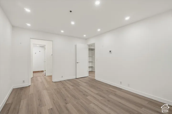 Recessed lighting illuminates the wood-finish flooring and white walls
