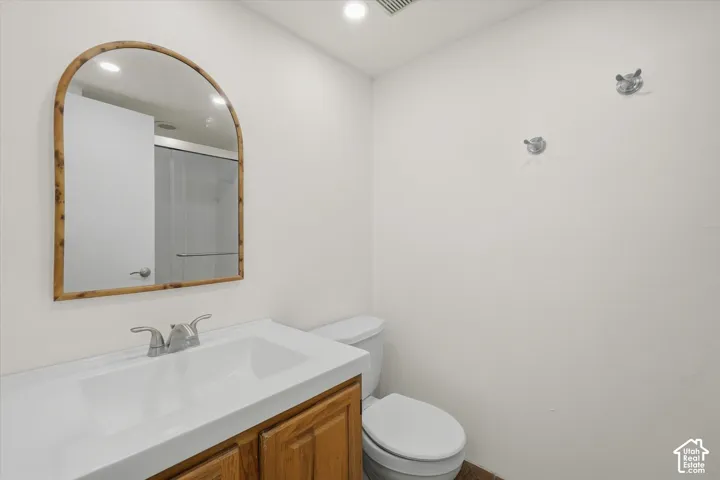 Bathroom featuring a wood-finish vanity with an integrated sink, polished chrome faucet, and an arched mirror