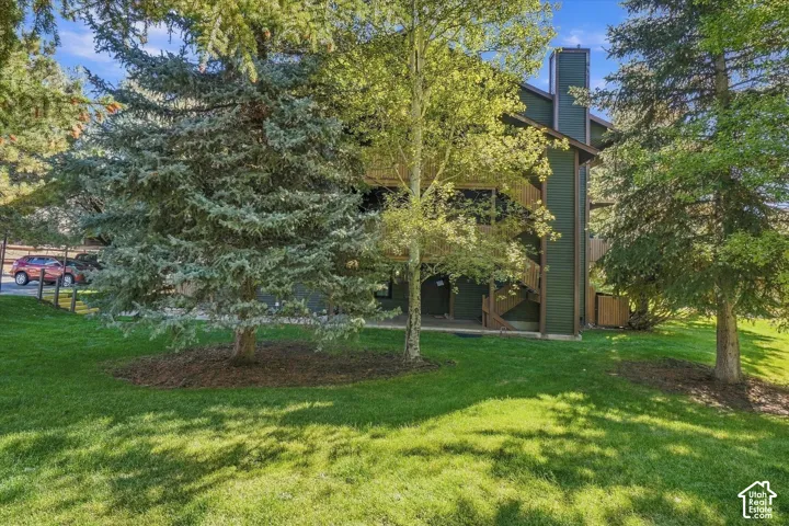 Multi-story exterior with dark green siding, multiple balconies, and a prominent chimney