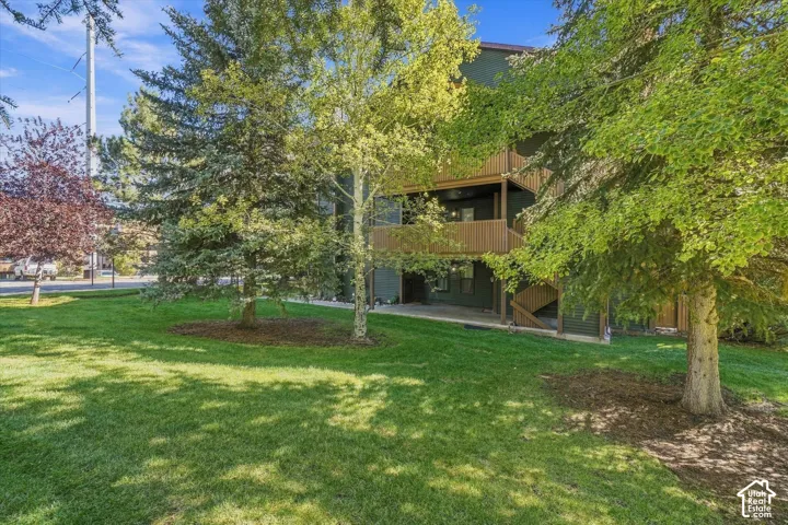 Manicured lawn with mature trees and a multi-story exterior featuring balconies and exterior staircases