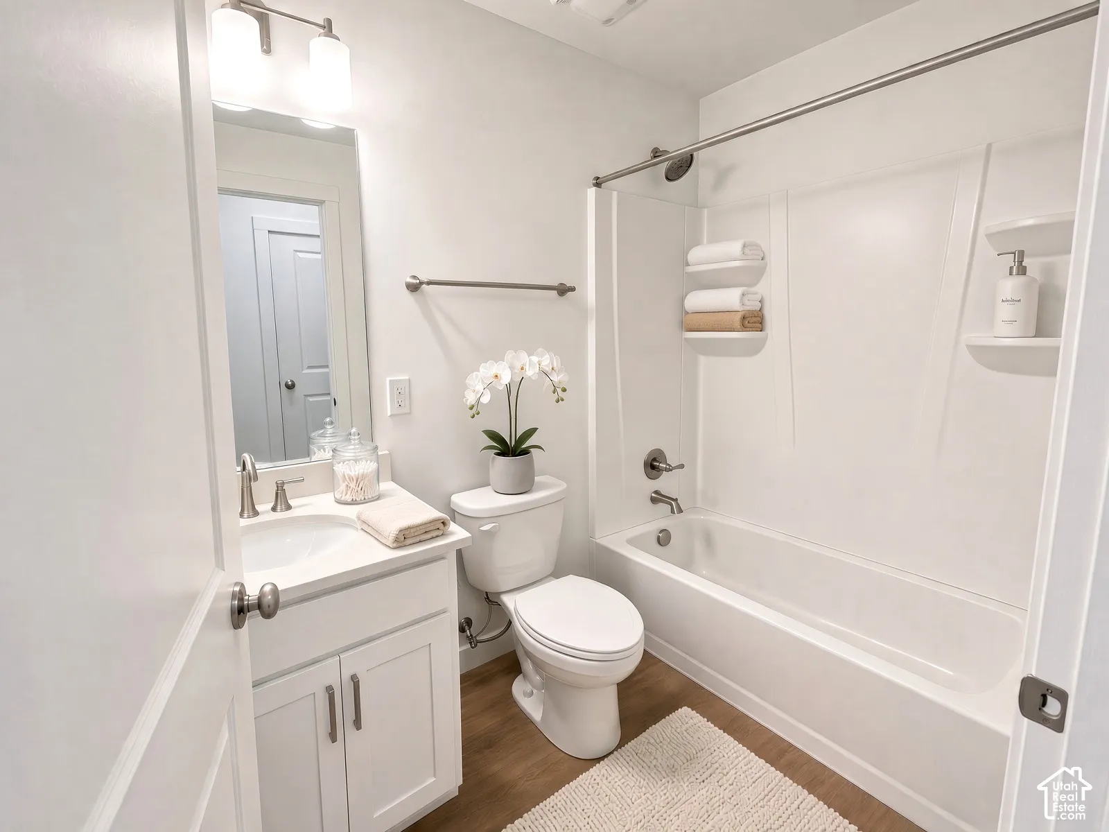 Bathroom featuring a single vanity with storage, a white countertop, and a built-in tub with a shower