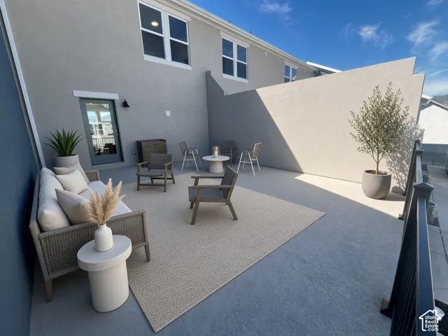 Private outdoor patio with a textured concrete surface, solid privacy walls, and a glass-paneled exterior door