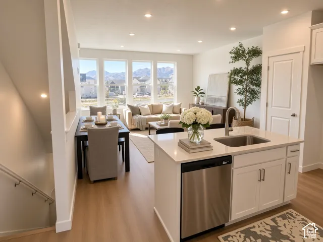Open-concept living space featuring wood-finish flooring, recessed lighting, and a kitchen island with an integrated stainless steel sink and dishwasher