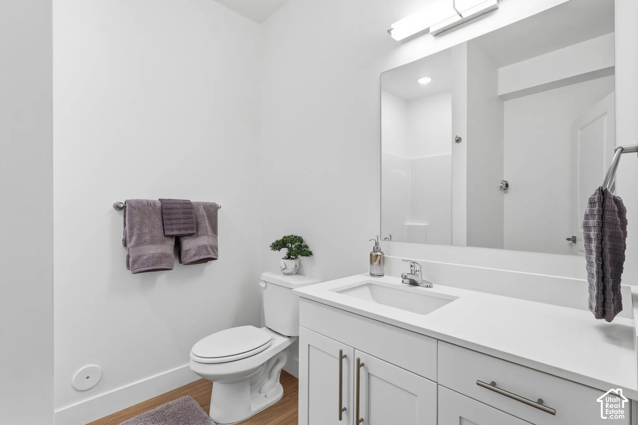" Model  not for rent" White vanity with integrated rectangular sink, chrome fixtures, and wood-finish flooring