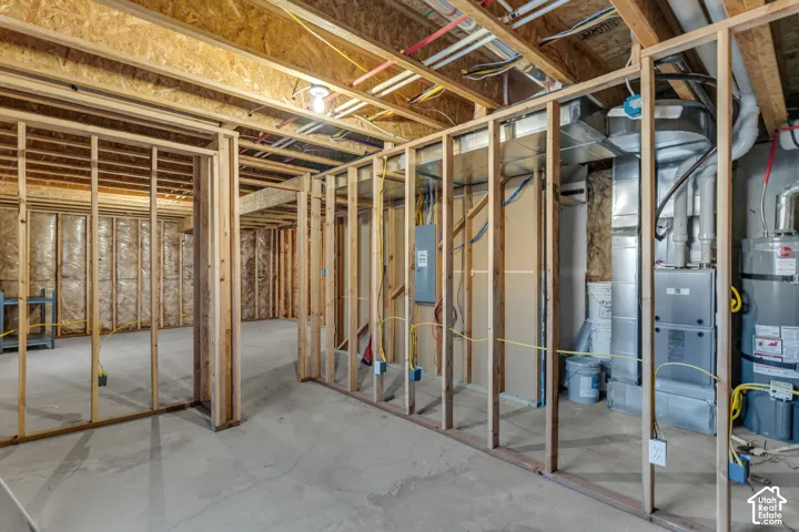 Unfinished basement framing, concrete floor, exposed joists, and visible utility systems