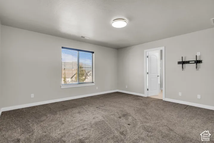 Plush carpet flooring, neutral paint palette, bright overhead lighting, and window with blinds