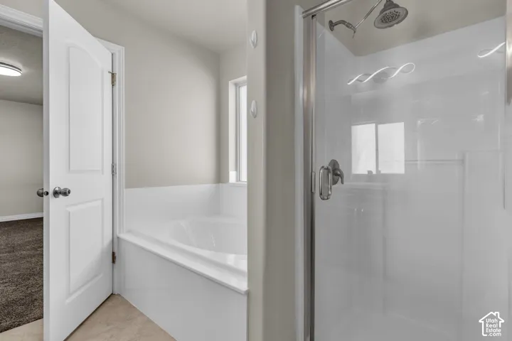 Walk-in shower with a glass enclosure, separate soaking tub, and tile flooring