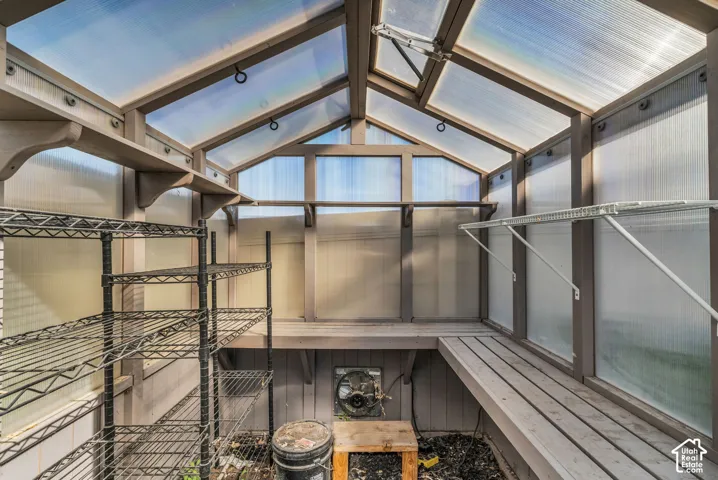 Greenhouse structure with translucent panels, wood-finish framing, and built-in shelving