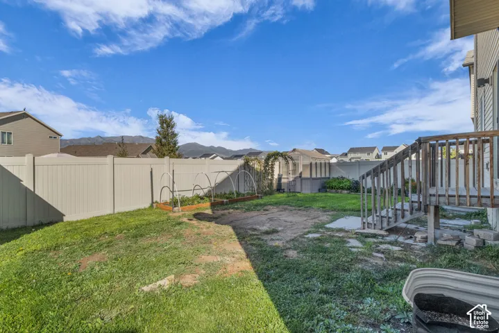 Expansive backyard with a full privacy fence, raised garden beds, and mountain scenery