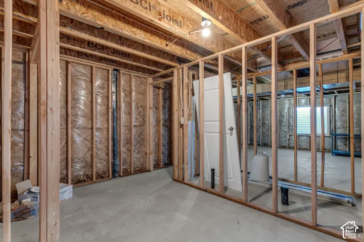 Unfinished basement featuring wood framing, exposed ceiling joists, concrete flooring, and a single window