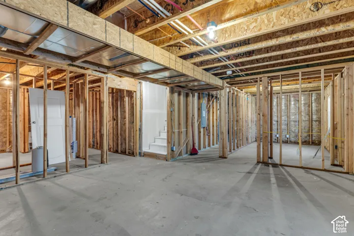 Unfinished basement with concrete flooring, exposed wood framing, and visible ceiling joists