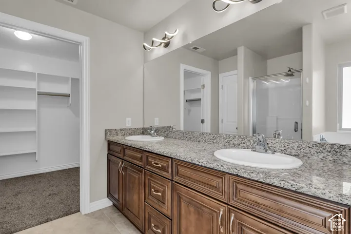 Double vanity with granite countertop, wood-finish cabinetry, and contemporary light fixtures