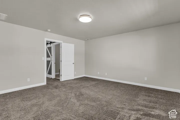 Spacious room with plush carpeting, neutral wall finishes, and a contemporary ceiling light fixture