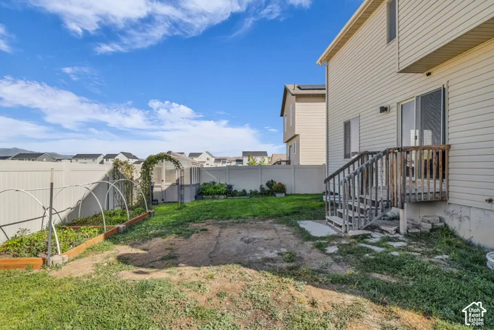 Outdoor patio with wooden deck and stairs, sliding glass door access, white vinyl fencing, and raised garden beds