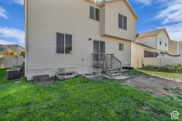 Vinyl siding exterior with a ground-level deck, sliding glass door access, and a partial grass lawn
