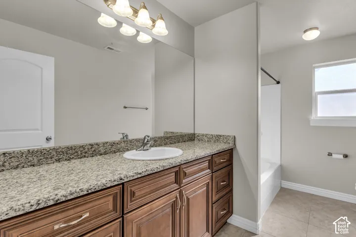 Vanity with an integrated sink, polished chrome faucet, and granite countertop