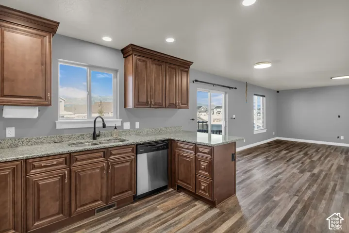 Kitchen featuring wood-finish cabinetry, light-toned countertops, and a stainless steel dishwasher