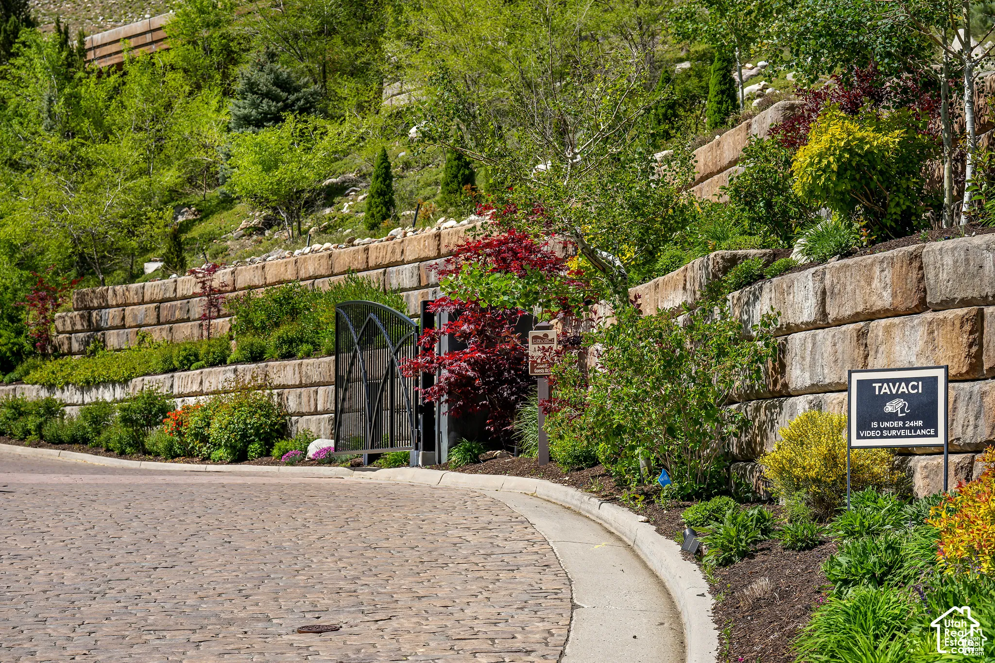 Cobblestone road leading to a landscaped hillside with tiered retaining walls