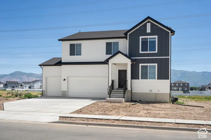 Contemporary exterior with dark gray and white siding, two-car garage, covered entry, and concrete driveway