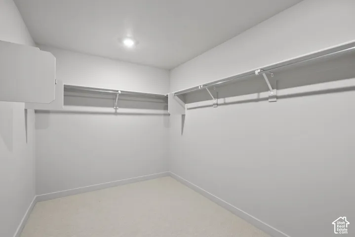 **DISLCAIMER**  Interiors do not show upgrades included. Carpeted walk-in closet featuring built-in shelving and hanging rods with integrated ceiling lighting