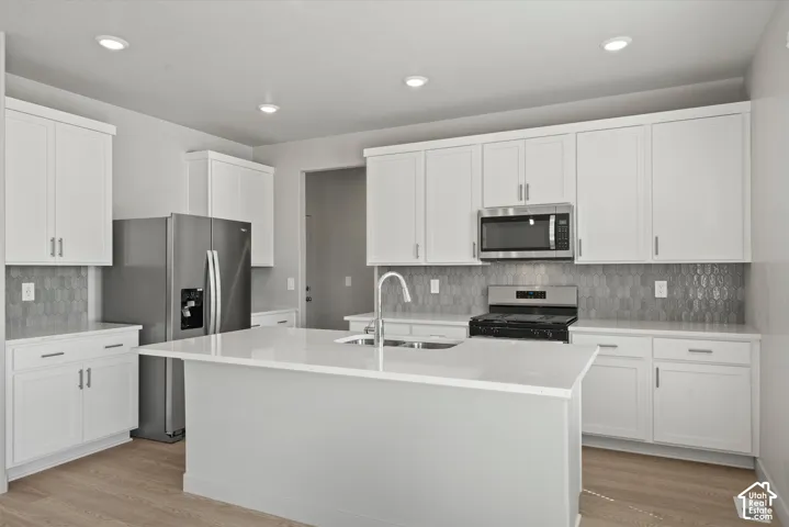 **DISLCAIMER**  Interiors do not show upgrades included. Kitchen featuring a central island, white cabinetry, integrated stainless steel appliances, a mosaic tile backsplash, and recessed lighting