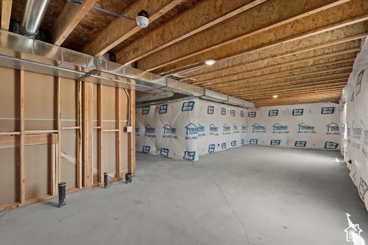 Unfinished basement featuring exposed wood joists, concrete flooring, and partial wall framing