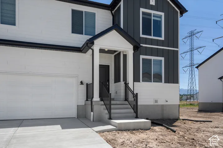 Two-story residence featuring a white and dark gray exterior, covered entry, and a concrete driveway