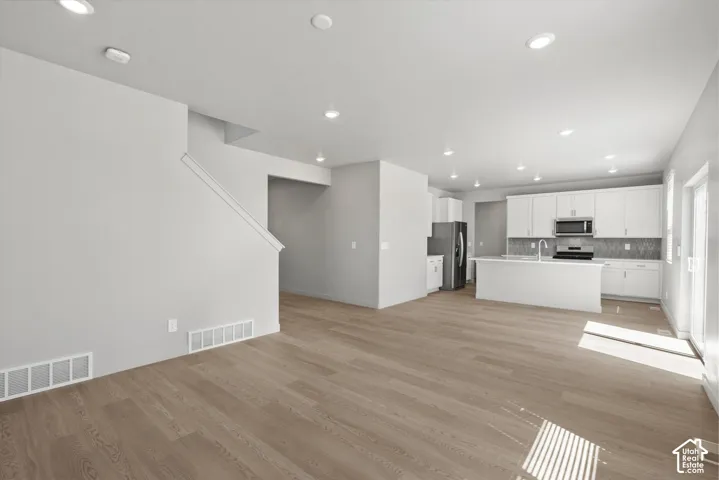 **DISLCAIMER**  Interiors do not show upgrades included. Open concept living area featuring wood-finish flooring, recessed lighting, and a modern kitchen with white cabinetry