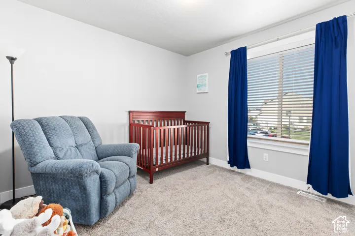 Neutral wall paint, textured carpeting, window with blinds, and white trim