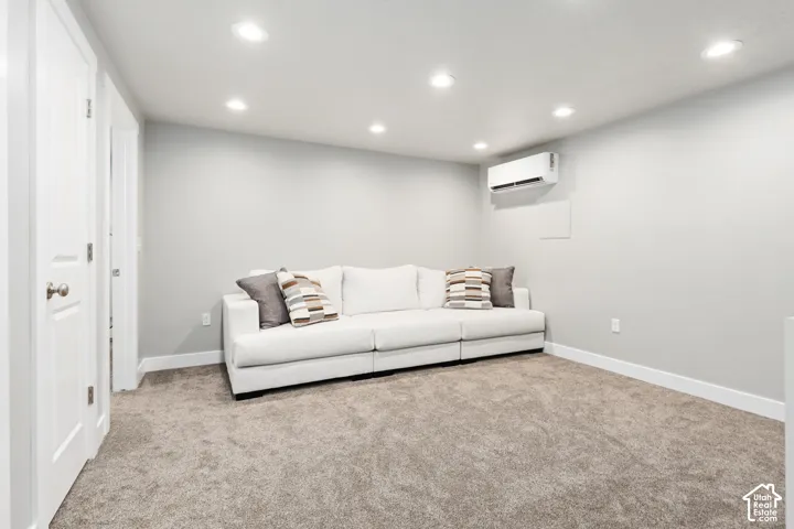 Recessed ceiling lighting, light gray wall paint, white interior doors, split-system air conditioning unit, and neutral carpet flooring