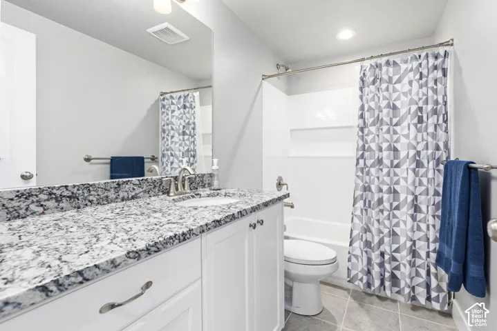 White vanity with brushed nickel hardware, speckled countertop, and a white integrated sink
