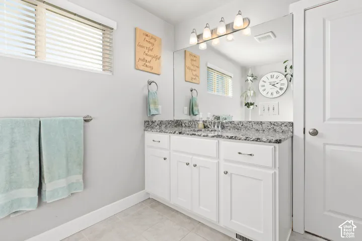 White vanity with shaker-style cabinetry, a granite-finish countertop, and an undermount sink