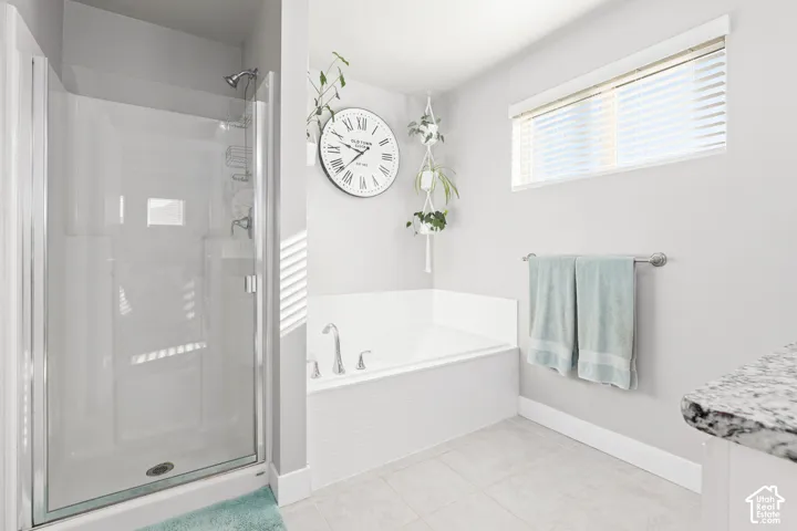 Glass-enclosed shower, built-in soaking tub, and a window with blinds