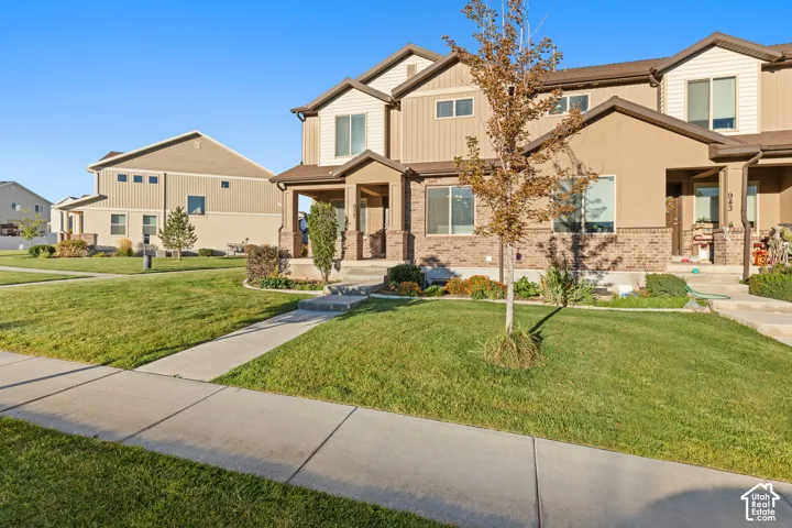 Townhome exterior featuring a combination of brick and siding, a covered entry, and a concrete pathway leading to the front door