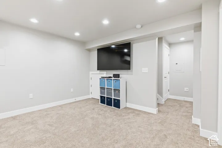 Carpeted recreation area with recessed lighting and a wall-mounted entertainment system