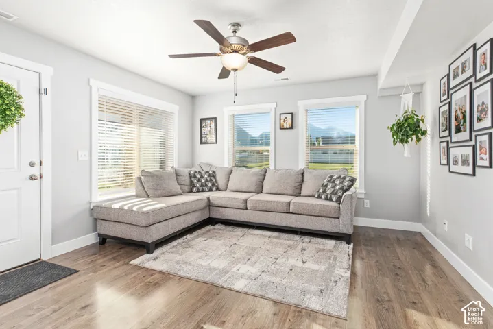 Wood-finish flooring throughout, multiple windows with blinds, recessed lighting, and a ceiling fan with integrated light
