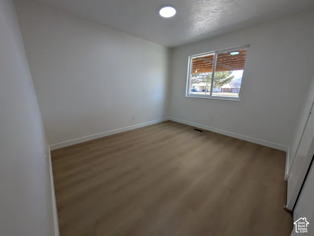 Light wood-finish flooring, white walls, recessed lighting, and a window with horizontal blinds