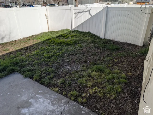 Enclosed yard area with a partial concrete patio and white privacy fencing