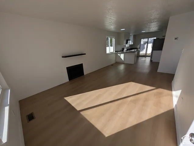 Wood-finish flooring throughout, featuring a fireplace with a black surround and mantle shelf