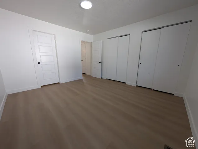 Light wood-finish flooring, white walls, and a recessed ceiling light
