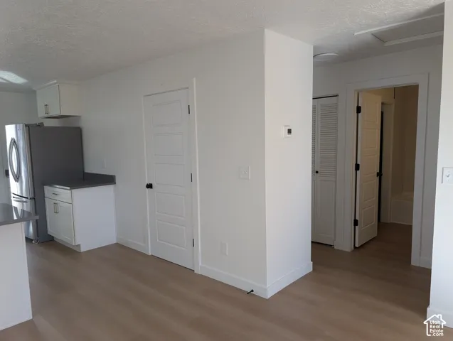 Wood-finish flooring throughout, white paneled doors, and a stainless steel refrigerator