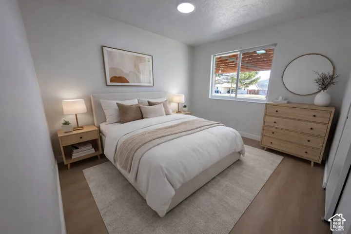 Light wood-finish flooring, recessed ceiling lighting, and a large window with blinds