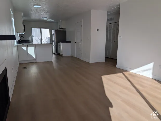 Open-concept living space with wood-finish flooring, recessed lighting, and white walls