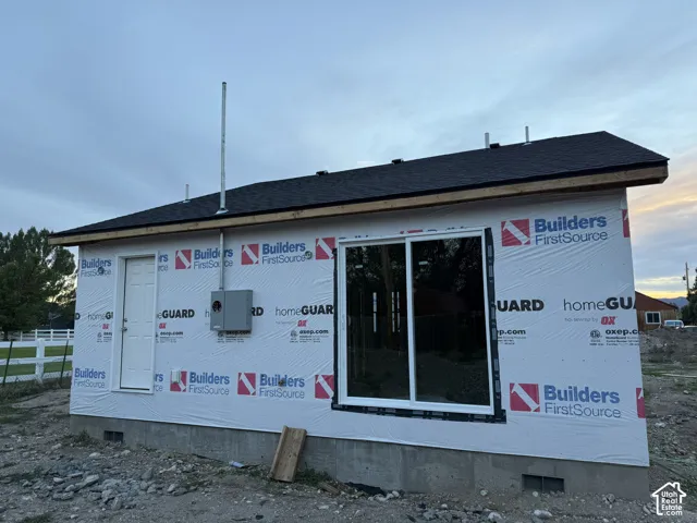 New construction featuring a dark shingle roof, white entry door, and large sliding glass door