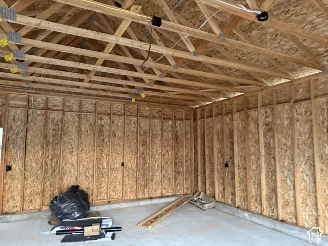 Exposed wood framing with engineered wood panels, concrete foundation, and open truss ceiling