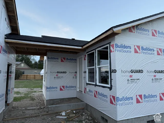 New construction framing with white window frames and a dark shingle roof