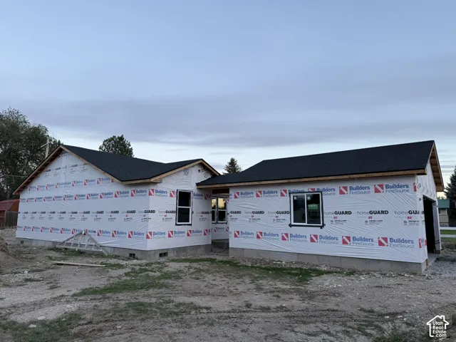 New construction with dark shingle roofing, white window frames, and foundation