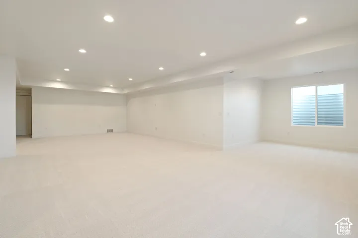 Expansive room featuring recessed lighting, light-toned carpeting, and a window with a horizontal blind