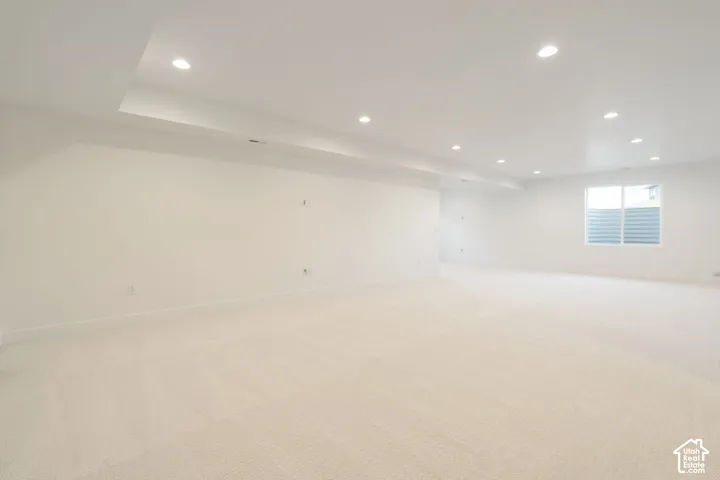 Expansive open-concept room featuring plush carpeting, recessed lighting, and a window with horizontal blinds